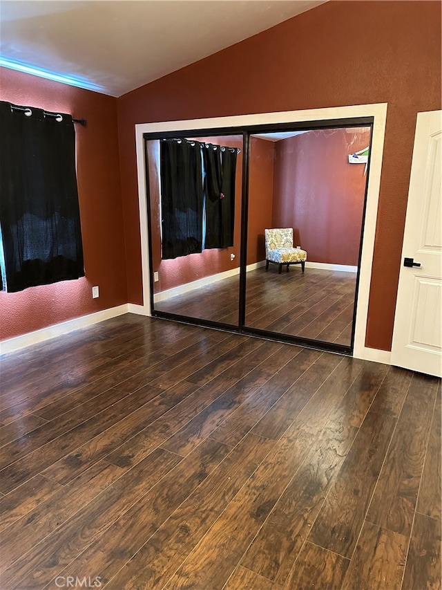 unfurnished bedroom with lofted ceiling, a closet, and hardwood / wood-style flooring