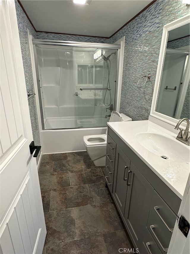 full bathroom with ornamental molding, combined bath / shower with glass door, vanity, and toilet