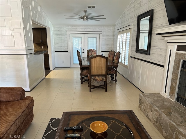 tiled dining area featuring a high end fireplace, lofted ceiling, ceiling fan, and french doors