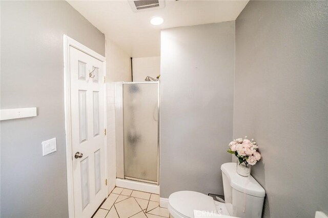 bathroom with toilet, tile patterned floors, and a shower with shower door