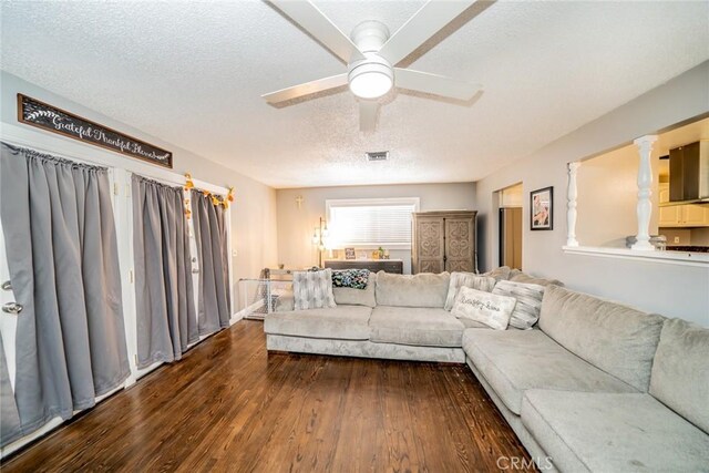 living room with ceiling fan, dark hardwood / wood-style flooring, and a textured ceiling