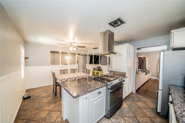 kitchen featuring white cabinetry, ceiling fan, white refrigerator, island exhaust hood, and black gas stove