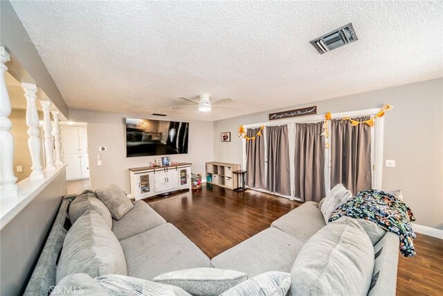 living room featuring hardwood / wood-style floors, a textured ceiling, decorative columns, and ceiling fan