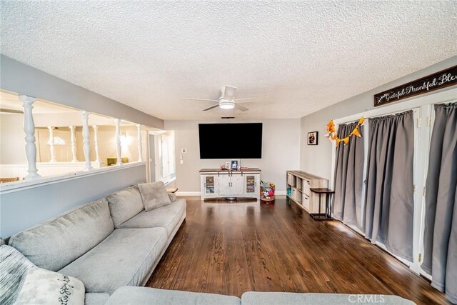 living room with a textured ceiling, dark hardwood / wood-style flooring, and ceiling fan