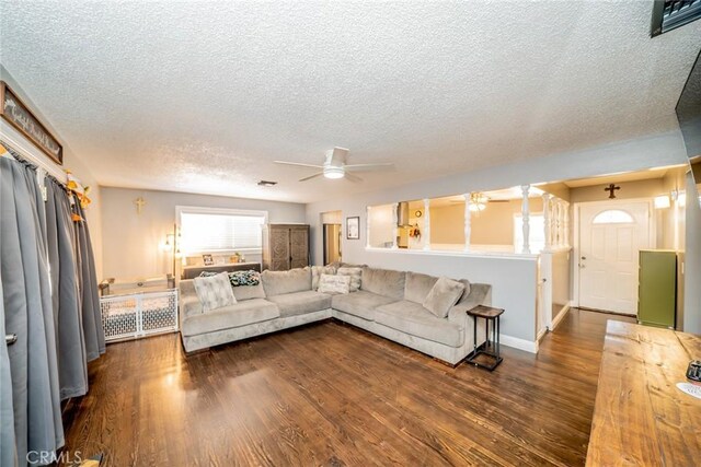 living room featuring ceiling fan, dark wood-type flooring, and a textured ceiling