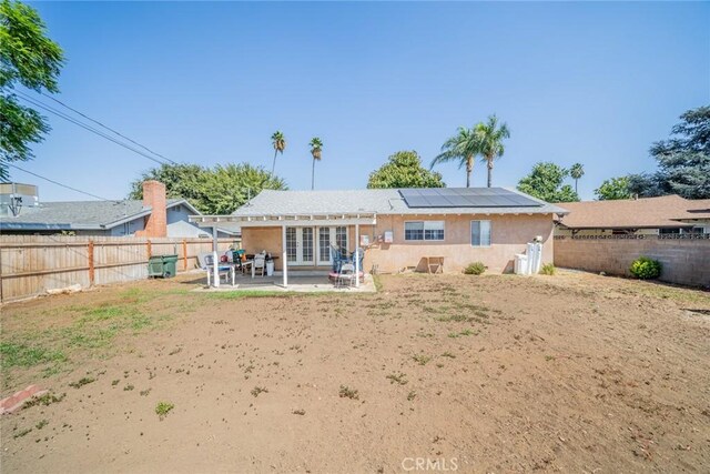 back of property featuring french doors, solar panels, and a patio area