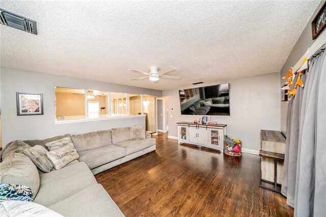 living room with ceiling fan, dark hardwood / wood-style flooring, and a textured ceiling