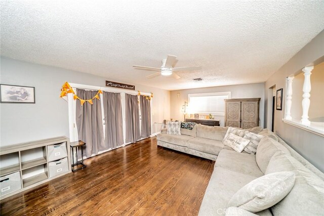 living room with ceiling fan, dark hardwood / wood-style flooring, and a textured ceiling