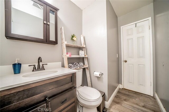 bathroom with hardwood / wood-style floors, vanity, and toilet