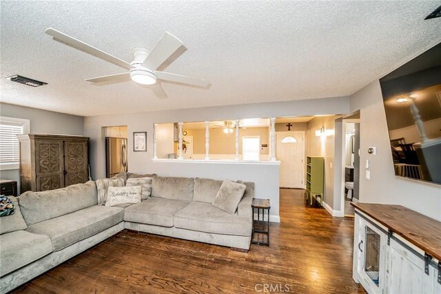 living room featuring a textured ceiling, ceiling fan, and dark wood-type flooring