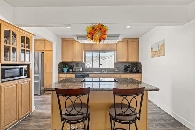 kitchen with a breakfast bar, a center island, backsplash, and appliances with stainless steel finishes