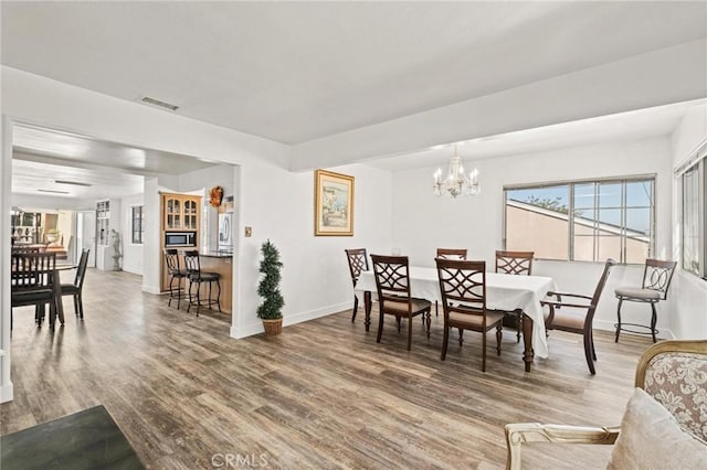 dining space with hardwood / wood-style floors and an inviting chandelier