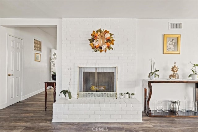 living room with dark wood-type flooring and a brick fireplace