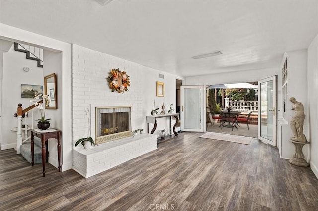 living room featuring dark hardwood / wood-style flooring and a brick fireplace