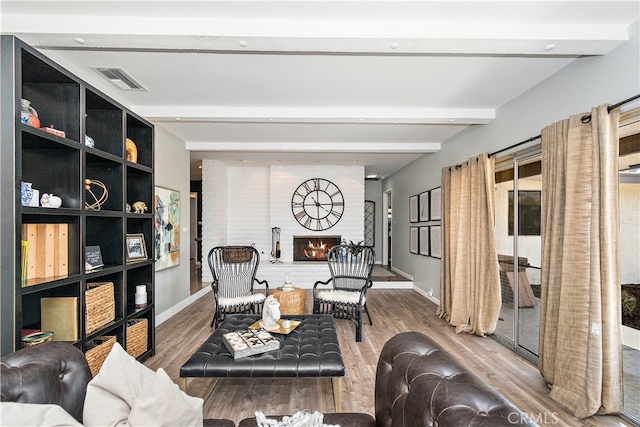 living room with wood-type flooring, a fireplace, and beam ceiling