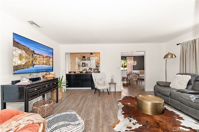 living room with wood-type flooring, bar, and a chandelier