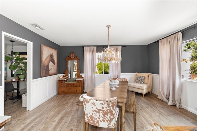 dining area featuring light wood-type flooring and a notable chandelier