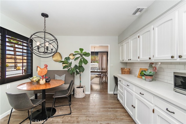 kitchen with decorative light fixtures, light wood-type flooring, a chandelier, and white cabinetry