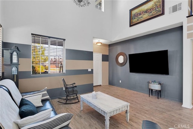 living room with wood-type flooring and a towering ceiling