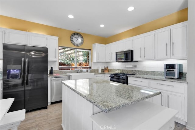 kitchen with sink, a kitchen island, appliances with stainless steel finishes, white cabinets, and light wood-type flooring