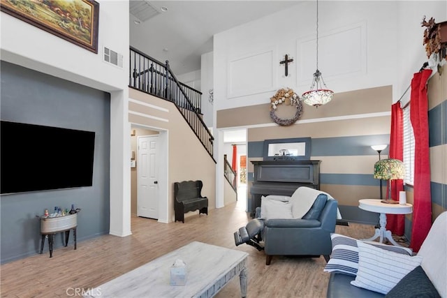 living room with a towering ceiling and light hardwood / wood-style flooring