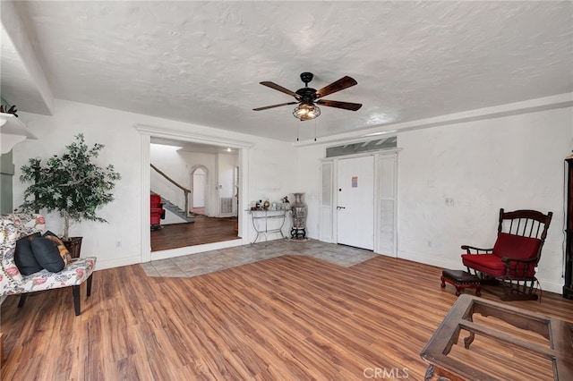 living area with ceiling fan, wood-type flooring, and a textured ceiling