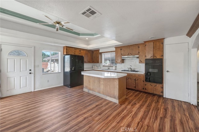 kitchen featuring a kitchen island, a textured ceiling, black appliances, dark wood-type flooring, and sink