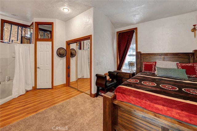 bedroom featuring light hardwood / wood-style flooring, a textured ceiling, a closet, and lofted ceiling