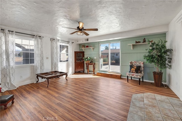 living area featuring ceiling fan, wood-type flooring, and plenty of natural light