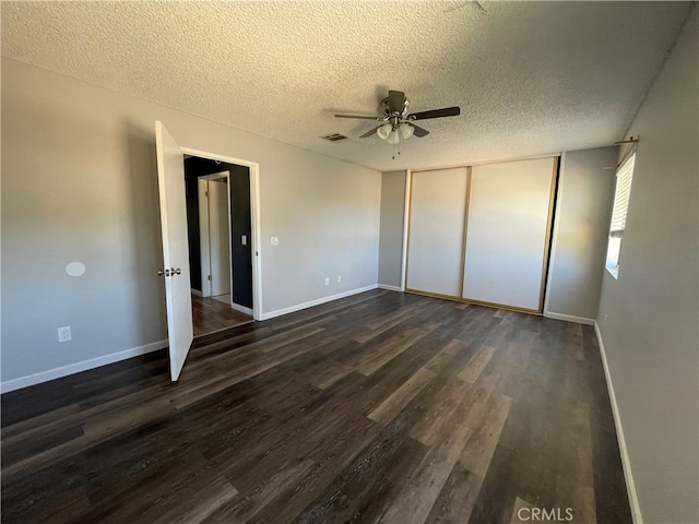 unfurnished bedroom with a textured ceiling, dark hardwood / wood-style floors, a closet, and ceiling fan