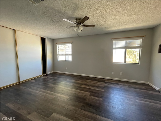 unfurnished bedroom featuring ceiling fan, a textured ceiling, and dark hardwood / wood-style floors