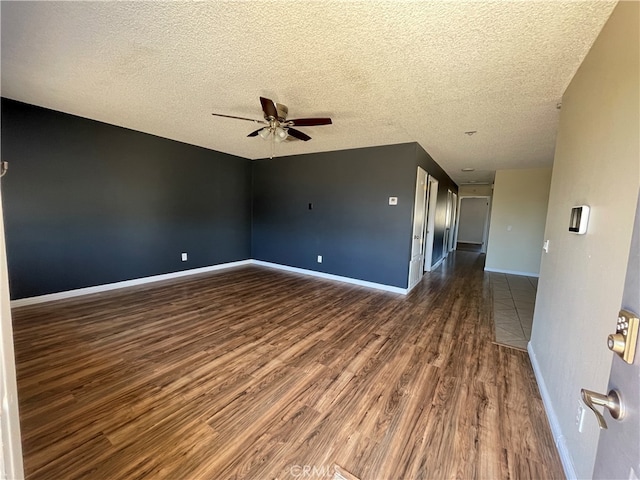 spare room featuring dark wood-type flooring, a textured ceiling, and ceiling fan