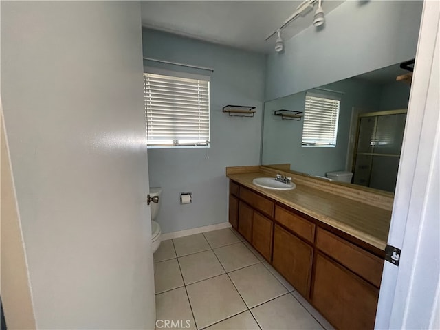 bathroom featuring toilet, a shower with shower door, vanity, and tile patterned floors