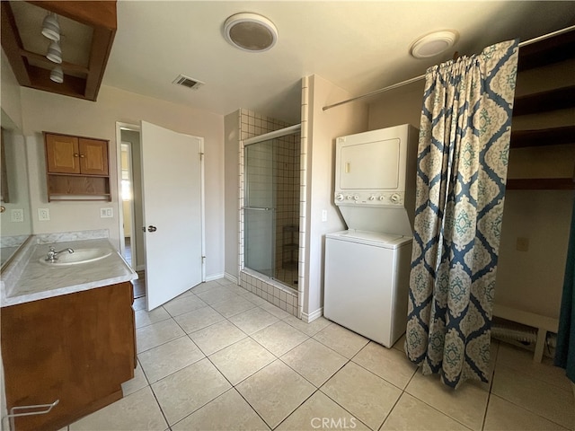 clothes washing area with sink, stacked washer / dryer, and light tile patterned floors