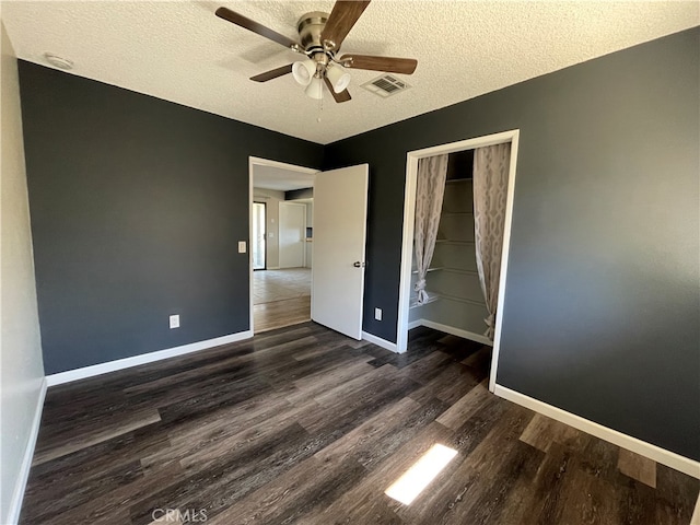 unfurnished bedroom featuring a closet, dark hardwood / wood-style floors, a textured ceiling, and ceiling fan