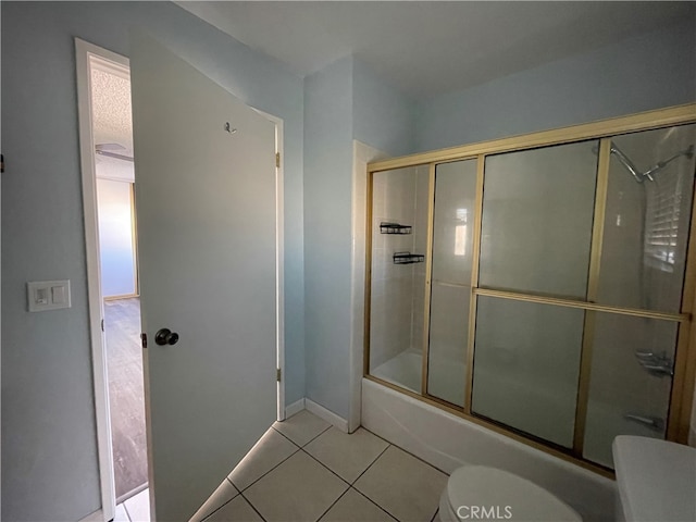 bathroom with bath / shower combo with glass door, toilet, and tile patterned flooring