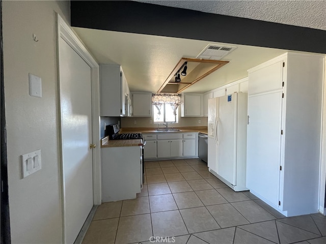 kitchen featuring light tile patterned floors, a textured ceiling, white cabinetry, sink, and white appliances