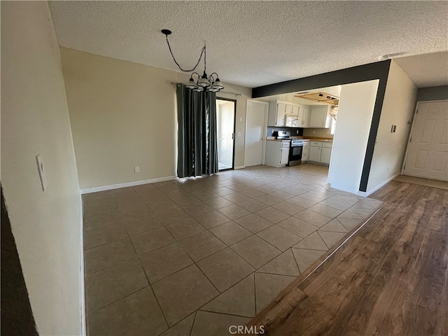 unfurnished living room featuring a notable chandelier, a textured ceiling, and light hardwood / wood-style floors