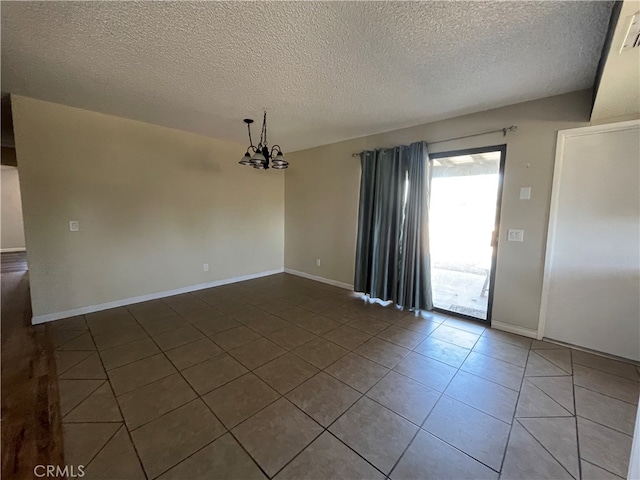 spare room featuring tile patterned floors, a notable chandelier, and a textured ceiling