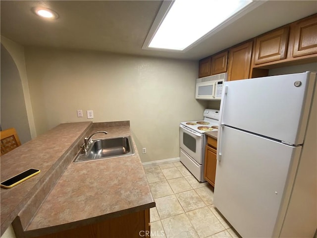 kitchen with light tile patterned floors, white appliances, and sink