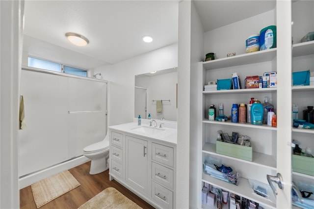 bathroom with vanity, hardwood / wood-style floors, toilet, and a shower with door