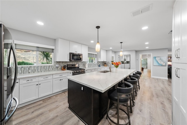 kitchen with white cabinets, appliances with stainless steel finishes, sink, and a healthy amount of sunlight