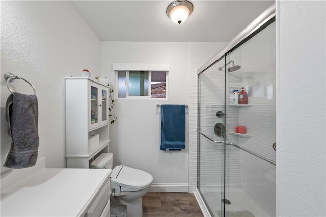 bathroom featuring vanity, a shower with shower door, toilet, and hardwood / wood-style flooring