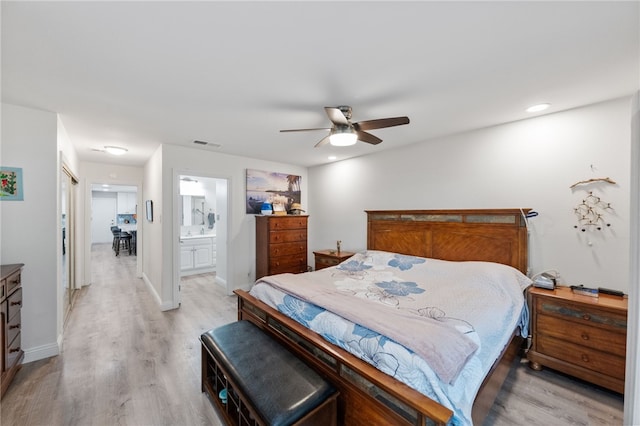 bedroom featuring light wood-type flooring, ensuite bath, and ceiling fan