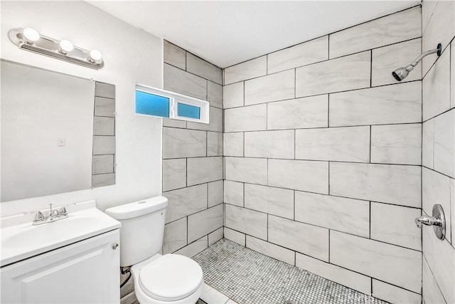 bathroom with tile patterned floors, vanity, toilet, and tiled shower