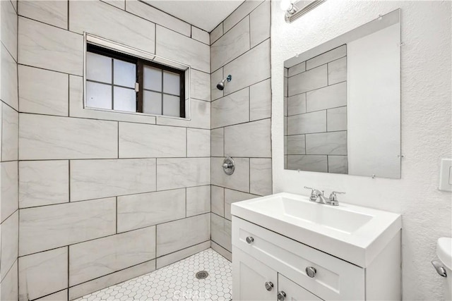 bathroom featuring a tile shower, vanity, and toilet