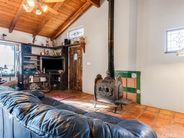 living room with a wood stove, wooden ceiling, ceiling fan, vaulted ceiling with beams, and tile patterned floors