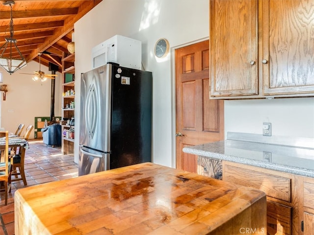 kitchen with hanging light fixtures, stainless steel refrigerator, lofted ceiling with beams, and butcher block countertops