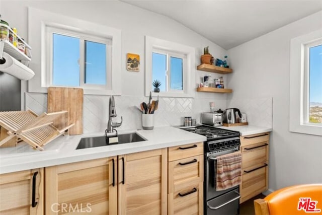 kitchen featuring decorative backsplash, vaulted ceiling, sink, light brown cabinets, and range with gas stovetop