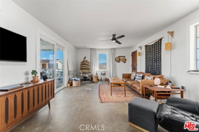 living room featuring a wealth of natural light, ceiling fan, and concrete flooring